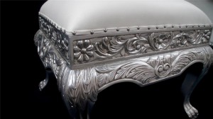 A LARGE ORNATE HEAVILY CARVED WEDDING STOOL IN SILVER LEAF AND SOFT WHITE FAUX LEATHER